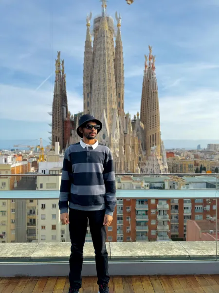 Kavindu Ravishan Perera on a rooftop terrace in Barcelona, with the towers of the Sagrada Família rising behind him