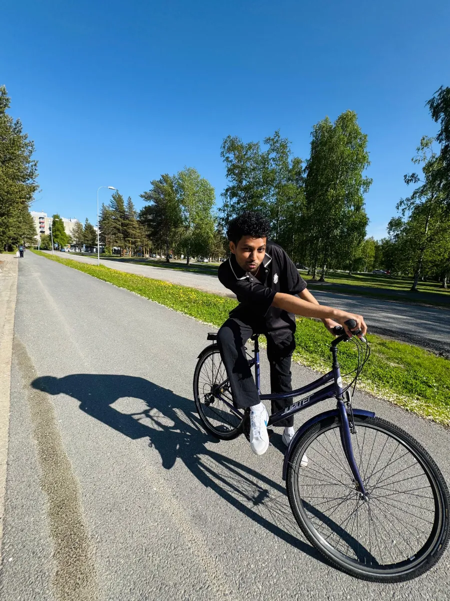 Kavindu Ravishan Perera on a bicycle on a sunny cycle path lined with trees