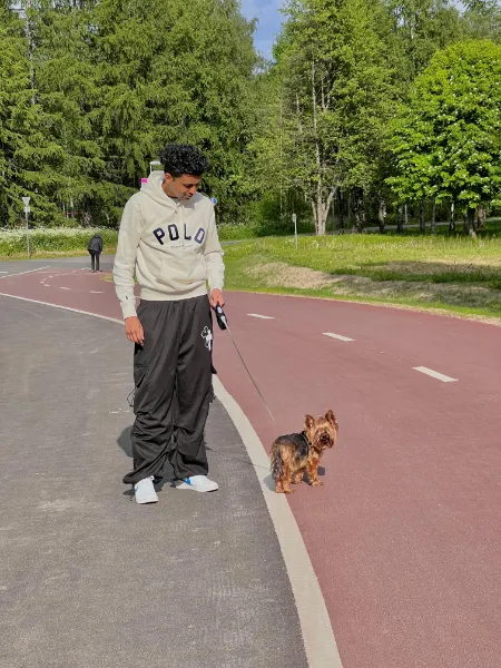 Kavindu Ravishan Perera walking a small dog along a red cycle path by the woods