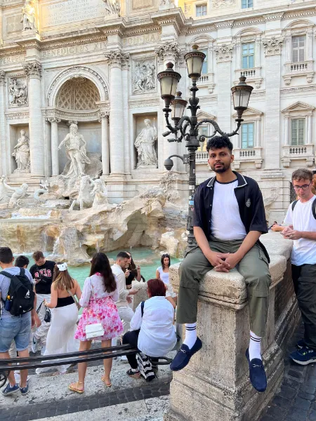 Kavindu Ravishan Perera sitting at the Trevi Fountain in Rome, among the crowds