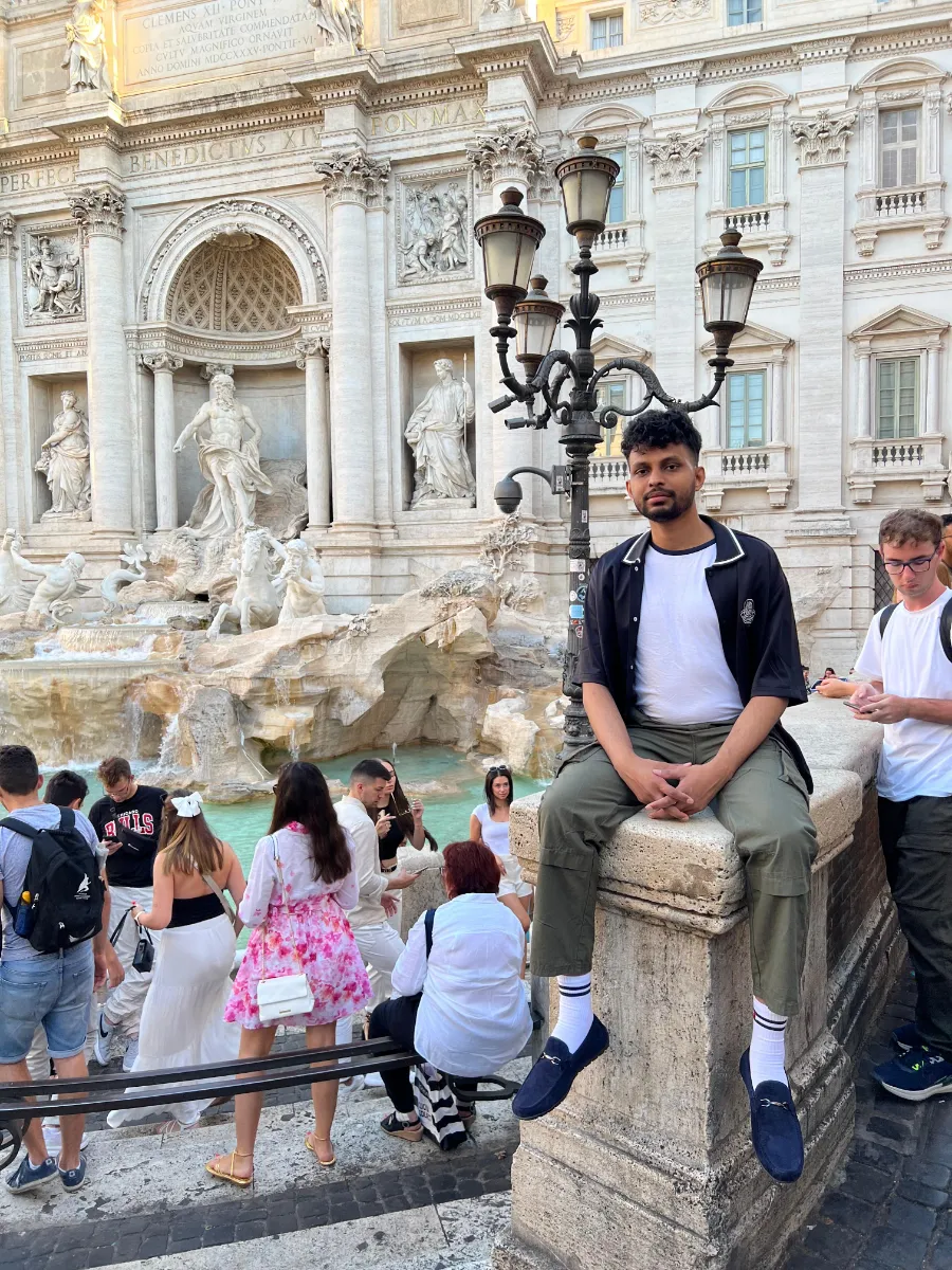 Kavindu Ravishan Perera sitting at the Trevi Fountain in Rome, among the crowds