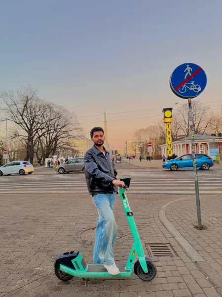 Kavindu Ravishan Perera on an electric scooter in a city square at dusk