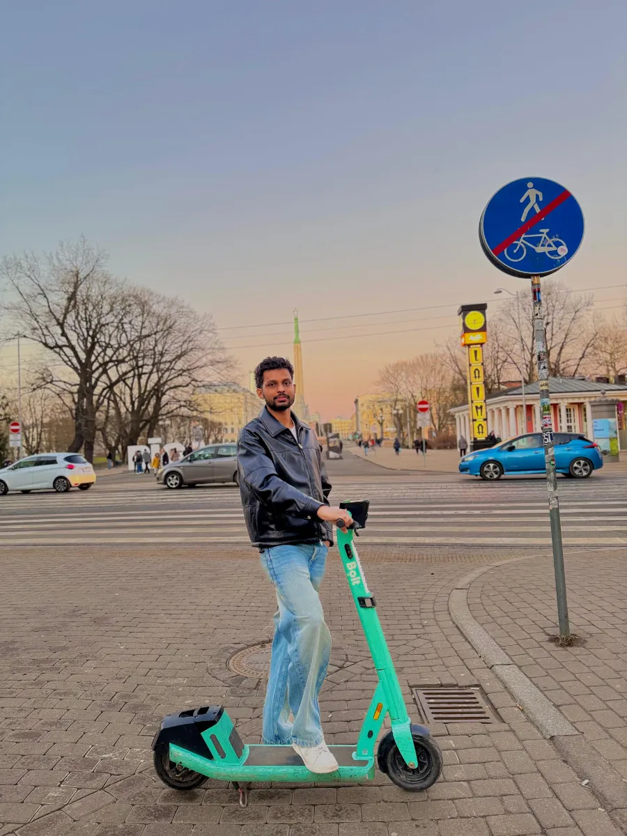 Kavindu Ravishan Perera on an electric scooter in a city square at dusk