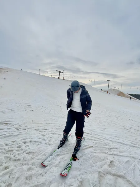 Kavindu Ravishan Perera skiing down a snowy slope under a grey sky